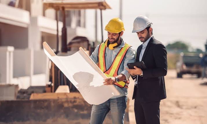 Engenheiro e responsável técnico avaliando planta de manutenção predial